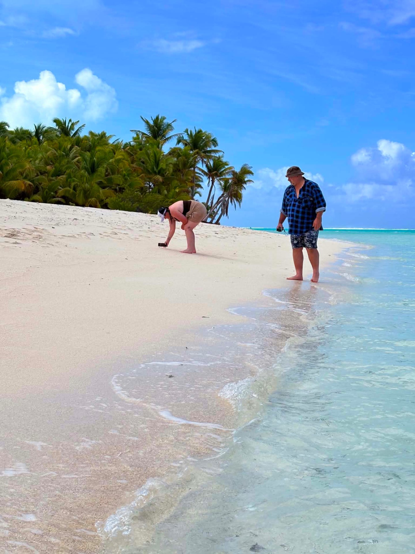 Guests walking along a white sandy shore in Aitutaki