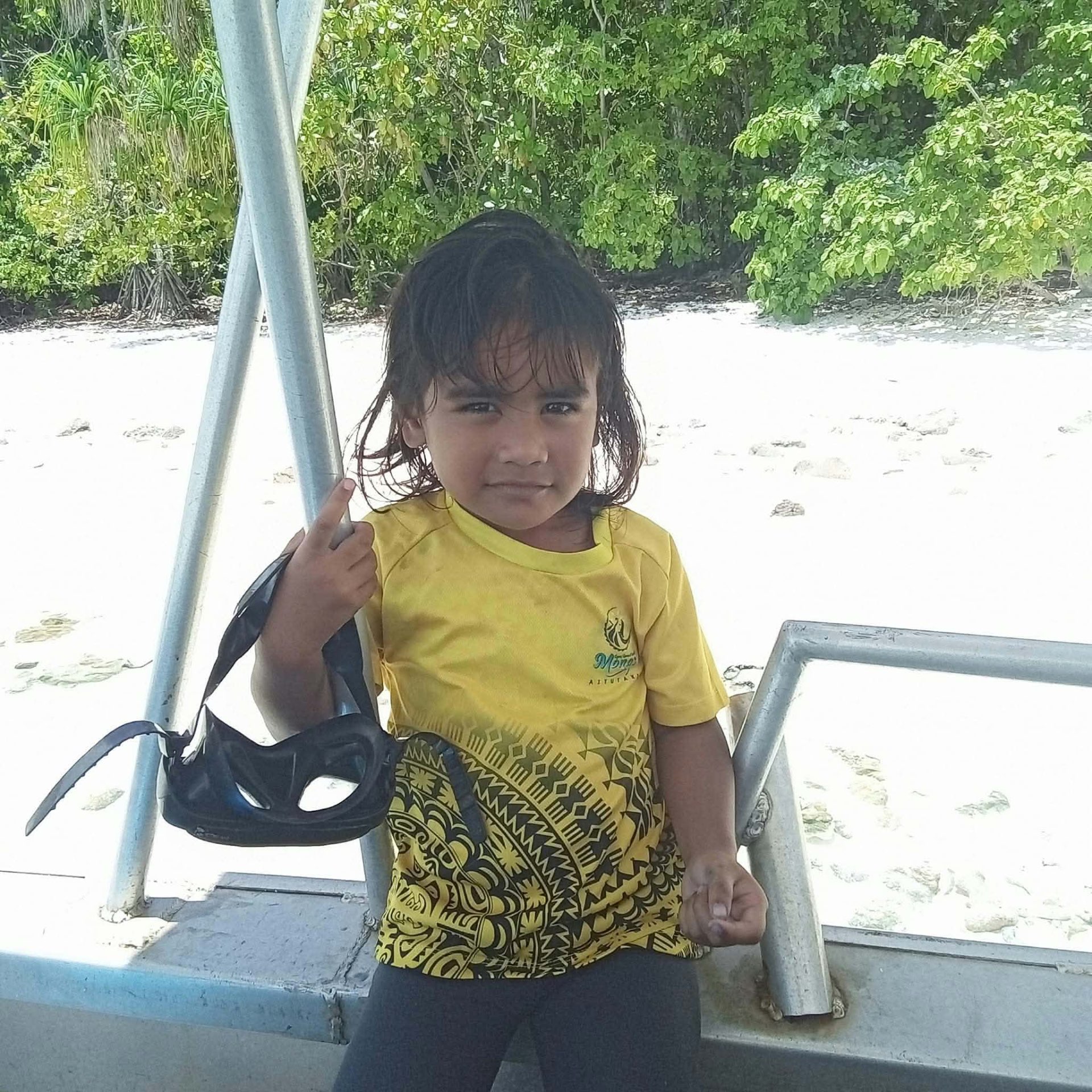A young child holding snorkelling gear beside Mona's Water Taxi