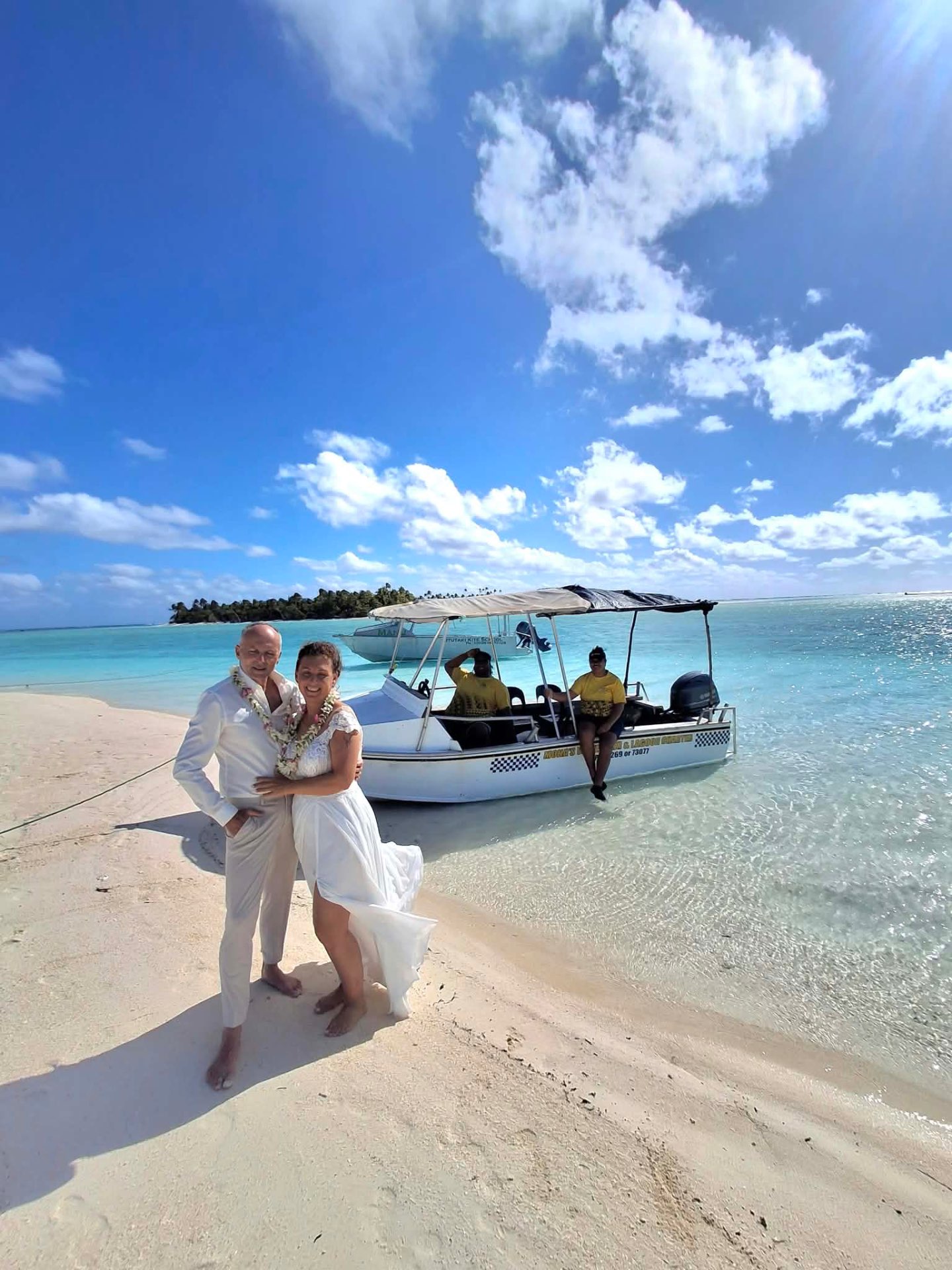 A wedding couple beside Mona's Water Taxi on an Aitutaki beach