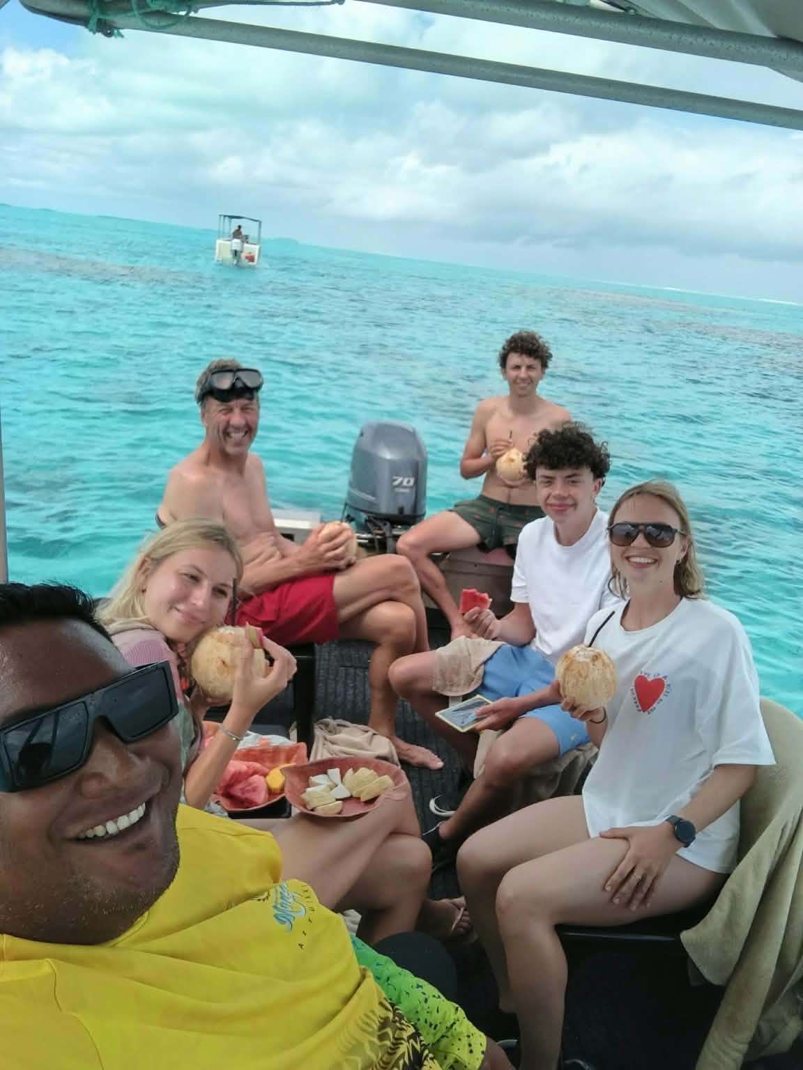 Captain Dan and guests enjoying fresh fruit and coconuts on the Aitutaki lagoon
